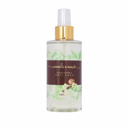 Frasco de spray para ambientes da marca Kailash, com rótulo em tons de marrom e verde, contendo a descrição "Canela e maçã" e informações sobre o volume de 200 ml. O frasco possui um bico pulverizador dourado.