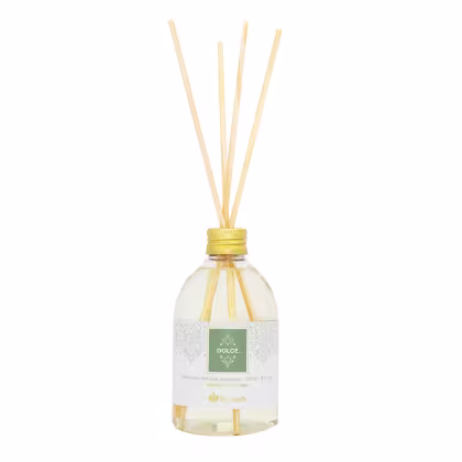 Difusor de aromas Dolce da Kailash, em frasco de vidro transparente com tampa e palitos de bambu, em cores claras e rótulo verde com detalhes decorativos.