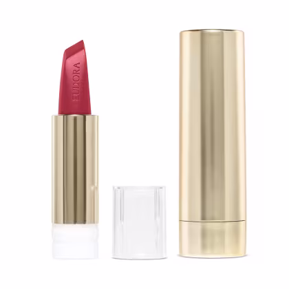 Na imagem o Batom Eudora Glam Amulips na cor Alaranjado Destemido, um tom de alaranjado terroso. O batom está aberto, revelando seu interior com o nome Eudora gravado no produto. A embalagem dourada transmite a elegância e qualidade do produto.