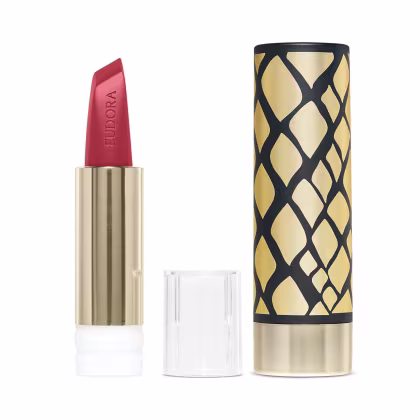 Do lado esquerdo da imagem há a embalagem dourada do produto aberta, desmontada e mostrando a bala do batom. Do lado direito há uma case com design geométrico sofisticado em preto e dourado.