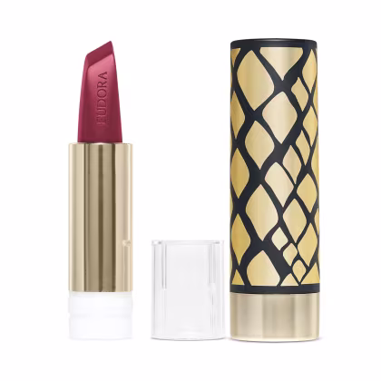 Na imagem o Batom Eudora Glam Amulips. O batom está aberto, revelando seu interior com o nome Eudora gravado no produto. A embalagem com design geométrico em preto e dourado, com um padrão de losangos que se entrelaçam, formam uma textura elegante.