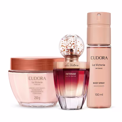 Conjunto de produtos da linha La Victorie Intense da marca Eudora. Inclui perfume, body spray desodorante corporal e creme hidratante desodorante corporal, em embalagens em tons rosados.