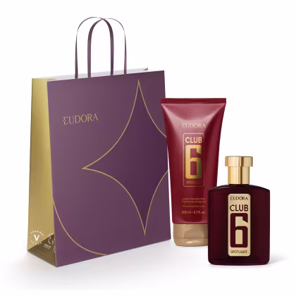 Conjunto de produtos de beleza da marca Eudora, incluindo um frasco de perfume Club 6 Spotlight e um tubo de loção corporal, acondicionados em uma sacola de compras de cor roxa com detalhes dourados.