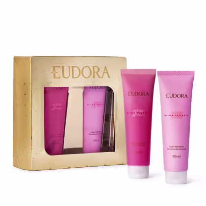 A imagem mostra kit da linha Niina Secrets da marca Eudora. O kit inclui uma caixa dourada com o nome "Eudora" em letras grandes, contendo dois tubos de loção hidratante corporal e sabonete líquido de 100ml cada, na cor rosa vibrante.