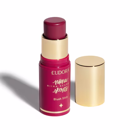 Blush em bastão Eudora Niina Secrets Daily, destampado com a tampa ao lado. Cor rosa com tampa dourada.