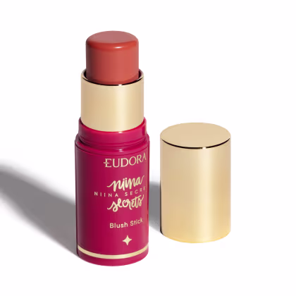Blush em bastão Eudora Niina Secrets Daily, destampado com a tampa ao lado. Cor rosa com tampa dourada.