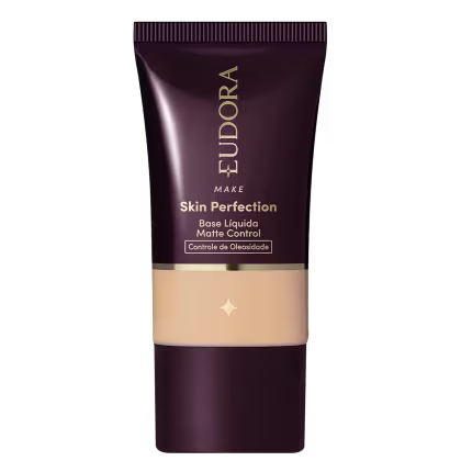 Tubo de base líquida para maquiagem da marca Eudora, com rótulo em tons escuros e dourados, apresentando o nome "Skin Perfection" e informações sobre controle de oleosidade.