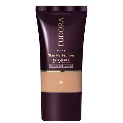 Tubo de base líquida para maquiagem da marca Eudora, com rótulo em tons escuros e dourados, apresentando o nome "Skin Perfection" e informações sobre controle de oleosidade.