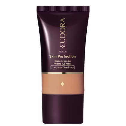 Tubo de base líquida para maquiagem da marca Eudora, com rótulo em tons escuros e dourados, apresentando o nome "Skin Perfection" e informações sobre controle de oleosidade.