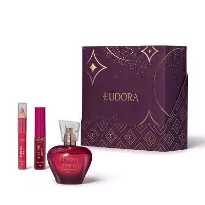 Conjunto de produtos da marca Eudora: Desodorante Colônia KissMe, o Gloss Labial e o Lápis Multifuncional na cor Cherry. Com uma caixa decorada com padrões dourados e estrelas em fundo roxo escuro, indicando ser um kit presente dia dos namorados.