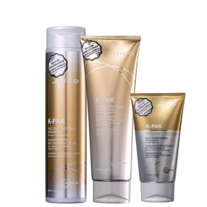 Produtos de cabelo da marca Joico, incluindo um frasco de shampoo reconstrutor K-Pak, um tubo de condicionador reconstrutor K-Pak e um tubo de tratamento capilar profundo K-Pak, todos em embalagens douradas e prateadas.