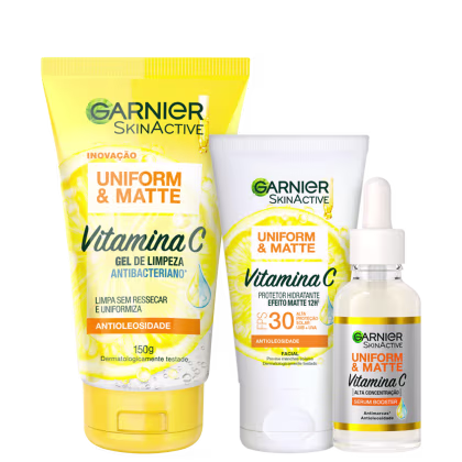 A imagem mostra três produtos de skincare da linha Garnier Skinactive Uniform & Matte com Vitamina C: um gel de limpeza antibacteriano em tubo amarelo, um protetor hidratante matte com FPS 30 em pote branco, e um sérum antioxidante em frasco transparente.