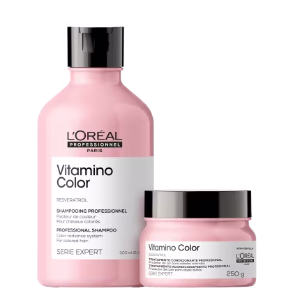 São produtos de cuidado capilar da linha Vitamino Color da L'Oréal Professionnel. Um é um shampoo em um frasco plástico rosa claro de 300ml, com tampa preta. O outro é um tratamento condicionante em um pote rosa claro de 250g, também com tampa preta.