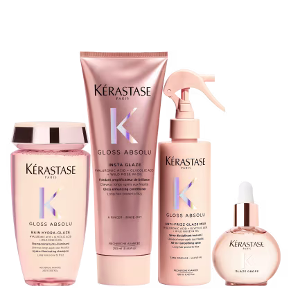 Produtos Kérastase em embalagens rosa e bege, incluindo shampoo, condicionador, spray e sérum para cabelos. As embalagens apresentam o logotipo da marca e informações sobre os benefícios dos produtos, como redução do frizz e brilho.