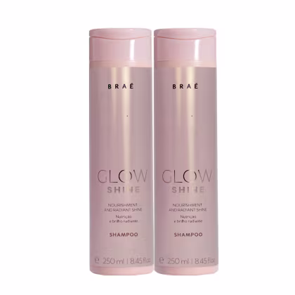 Dois frascos de shampoo Glow Shine da marca Brae. Embalagens cilíndricas de plástico rígido na cor rosa claro perolado. Rótulos dourados com o nome da marca Braé.