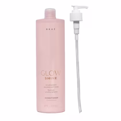 Condicionador Glow Shine da marca Brae. Embalagem plástica rosa claro com bomba dosadora branca. Rótulo com o nome do produto "Glow Shine" e descrição em letras douradas. Frasco de 1L. Design minimalista e elegante.