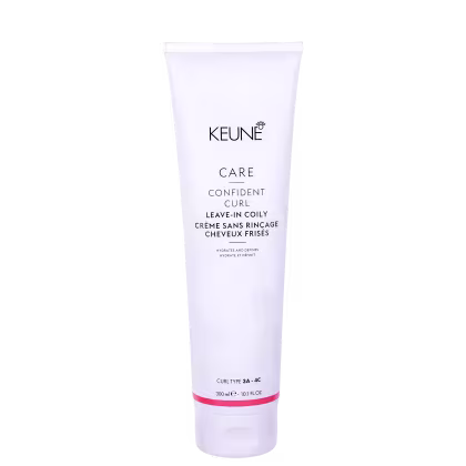 O produto apresentado é um creme leave-in da linha Confident Curl da marca Keune. A embalagem é um tubo branco com o logotipo da marca e o nome do produto "Confident Curl Leave-in Coily Creme".