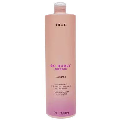 Shampoo para cabelos crespos da linha Go Curly da marca Braé. Embalagem plástica cilíndrica na cor rosa claro Descrição adicional: "Nutrição e limpeza suave dos fios".