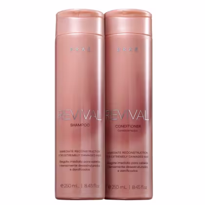 São dois frascos de plástico rígido na cor rosa metálico, contendo shampoo e condicionador da linha Revival da marca Brae. Os frascos têm formato cilíndrico e tampa rosqueável na mesma tonalidade.