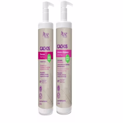 Dois frascos brancos de shampoo e ativador/modelador de cachos da marca Apise Cosméticos, com rótulos em tons de roxo e branco. Os produtos são indicados para cabelos cacheados, com informações sobre serem 100% veganos e de uso diário.