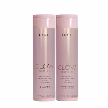 Dois frascos de plástico rosa claro de 250ml cada, contendo shampoo e condicionador da linha Glow Shine da marca Braé. Os frascos têm formato cilíndrico e tampas da mesma cor. Nas embalagens, está escrito "Glow Shine" em letras maiúsculas.