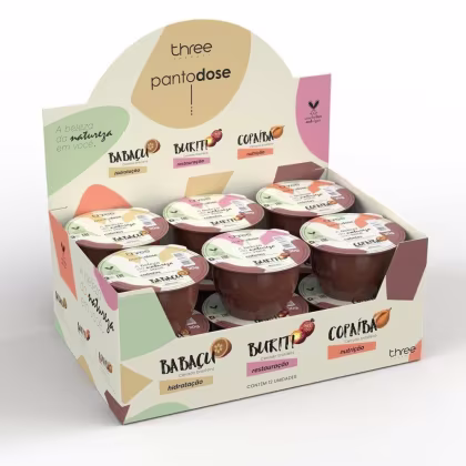 Caixa de papelão com produtos Three Therapy, incluindo potes de creme com rótulos de "Babaçu", "Buriti" e "Copaíba", destacando os benefícios de hidratação, restauração e nutrição.