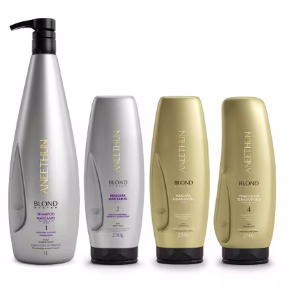 A imagem mostra um kit de cabelos com 4 produtos da linha Blond System de Aneethun. Sendo um shampoo, duas máscaras capilares, uma na cor prata e outra na cor dourada e um finalizador em um frasco dourado.