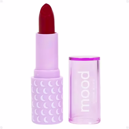 Batom da marca Ruby Rose. O batom possui uma embalagem de plástico lilás com um design de luas brancas. O próprio batom é de cor vermelha intensa. A embalagem também exibe o nome da marca "Ruby Rose" em letras brancas.