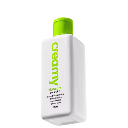 A imagem mostra o Creamy Ácido Tranexâmico Solução um frasco retangular transparente de tônico facial cor branca com tampa verde.