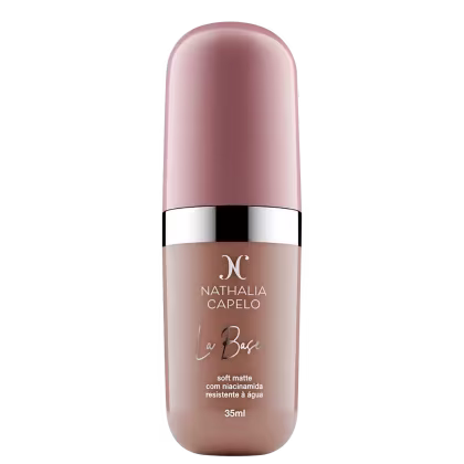 Frasco de maquiagem de base líquida da marca Nathalia Capelo, na cor rosa claro, com rótulo em branco e preto contendo o nome da marca e o nome do produto "La Base".