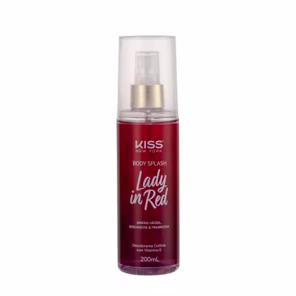 A imagem mostra o Body Splash em uma embalagem com cores vermelho e dourado, apresentando o logotipo Kiss New York. A tampa é transparente e traz um detalhe dourado na válvula spray.