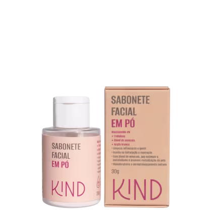 A imagem mostra um frasco pequeno redondo transparente com tampa branca ao lado da caixa retangular do produto. O rótulo e a caixa são bege, com letras pretas e rosa, com marca em destaque.