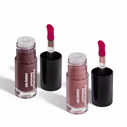 Conjunto de produtos de maquiagem da marca Quem Disse, Berenice? incluindo dois frascos de vidro com líquidos em tons de rosa e marrom, e dois tubos de batom vermelho em embalagens pretas.