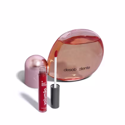 Frasco de perfume Desobediente da marca Quem Disse, Berenice, com tampa rosada e corpo transparente em tom alaranjado. Acompanha um batom líquido vermelho da mesma marca.