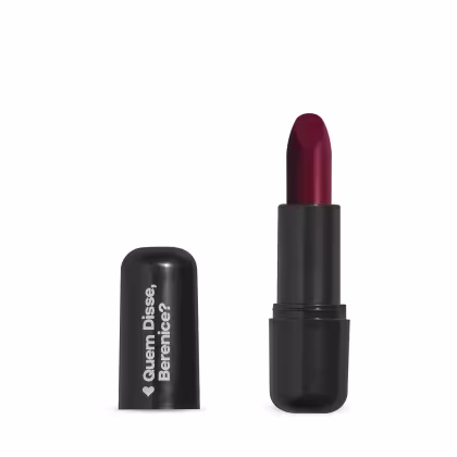 O produto apresentado na imagem é um batom da marca Quem Disse, Berenice?. O batom possui uma embalagem preta e o produto em si é de cor vermelha escura. O rótulo da embalagem exibe o nome da marca "Quem Disse, Berenice?" em letras brancas.