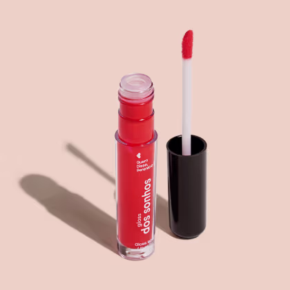 Frasco cilíndrico transparente contendo um gloss labial vermelho. Rótulo na embalagem com o nome do produto "Gloss dos Sonhos" e a descrição "Quem disse, berence?". Ao lado, a tampa preta do produto, que acompanha um aplicador de espuma.