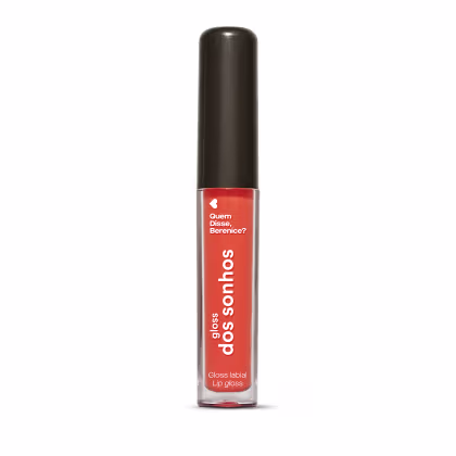 A imagem mostra um gloss labial em uma embalagem cilíndrica com a tampa preta e o tubo transparente permite ver o tom coral brilhante do gloss e a marca Quem disse, Berenice? e a linha estampados no frasco.