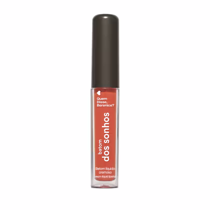 A imagem mostra um batom labial em uma embalagem cilíndrica com a tampa preta e o tubo transparente permite ver o tom laranja brilhante do batom e a marca Quem disse, Berenice? e a linha estampados no frasco.