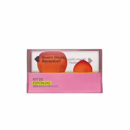 O kit é composto por duas esponjas de diferentes formatos, uma redonda e outra em formato de gota, ambas na cor laranja. A embalagem é uma caixa retangular rosa, com o texto "Kit de Esponjas QDB Dupla Infalível" impresso na parte frontal.