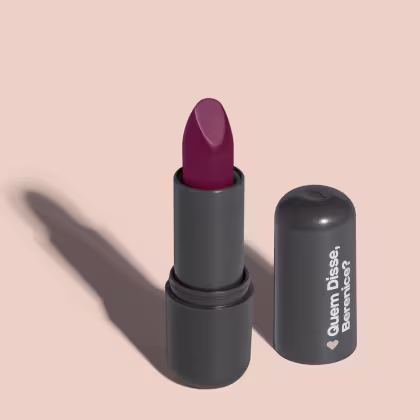 O produto apresentado na imagem é um batom da marca Quem Disse, Berenice?. O batom possui uma embalagem preta e o produto em si é de cor vinho escuro. O rótulo da embalagem apresenta o nome da marca "Quem Disse, Berenice?" em letras brancas.