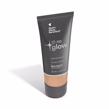 O produto apresentado é uma base líquida da marca Tô no Glow, com embalagem em tubo plástico de cor cinza escura. O rótulo exibe o nome da marca e o texto "Radiância natural, leveza e conforto" em letras brancas.