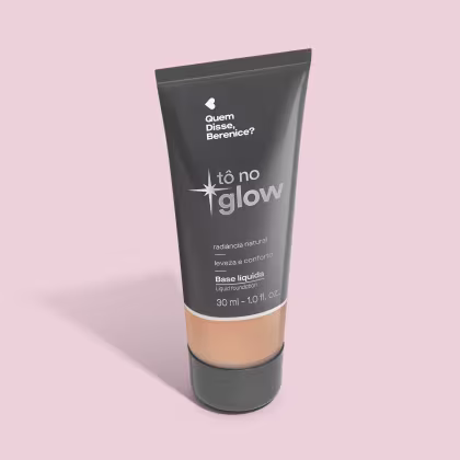 O produto apresentado é uma base líquida da marca Tô no Glow, com embalagem em tubo plástico preto e branco. O rótulo exibe o nome da marca e a descrição "Radiância natural, leveza e conforto". O produto é classificado como "Base líquida".