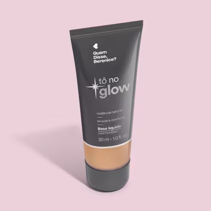 O produto apresentado é uma base líquida da marca Tô no Glow, com embalagem em tubo plástico preto e branco. O rótulo exibe o nome da marca e a descrição "Radiância natural, leveza e conforto". O produto é classificado como "Base líquida".