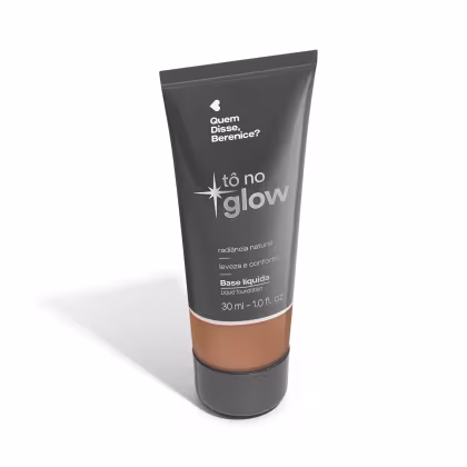 O produto apresentado é uma base líquida da marca Tô no Glow, com embalagem em tubo plástico de cor cinza escura. O rótulo exibe o nome da marca e o texto "Radiância natural, leveza e conforto" em letras brancas.