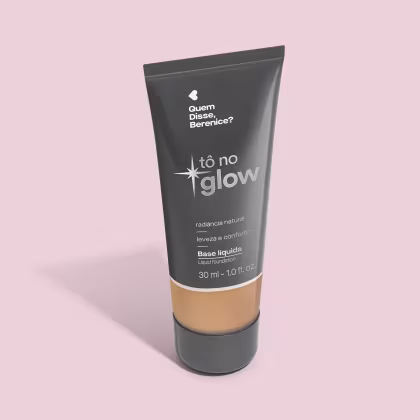 O produto apresentado é uma base líquida da marca Tô no Glow, com embalagem em tubo plástico preto e branco. O rótulo exibe o nome da marca e a descrição "Radiância natural, leveza e conforto". O produto é classificado como "Base líquida".