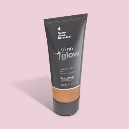 O produto apresentado é uma base líquida da marca Tô no Glow, com embalagem em tubo plástico preto e branco. O rótulo exibe o nome da marca e a descrição "Radiância natural, leveza e conforto". O produto é classificado como "Base líquida".