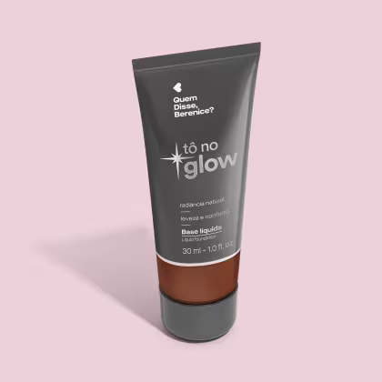O produto apresentado é uma base líquida da marca Tô no Glow, com embalagem em tubo plástico preto e branco. O rótulo exibe o nome da marca e a descrição "Radiância natural, leveza e conforto". O produto é classificado como "Base líquida".