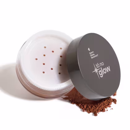 Pó compacto em embalagem de vidro com tampa cinza, contendo partículas brilhantes. O rótulo indica "Tô no Glow", sugerindo tratar-se de um produto de beleza com efeito iluminador.