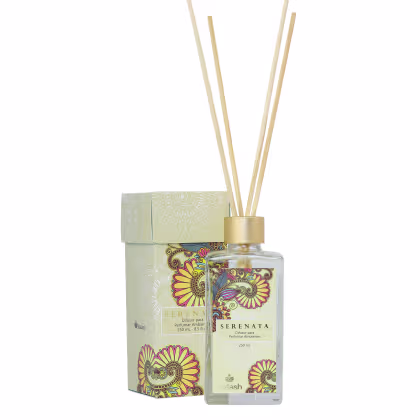Difusor de aromas Serenata da marca Kailash, em embalagem decorada com padrões florais em tons de verde e amarelo, contendo um frasco de vidro transparente com líquido e varetas de madeira.