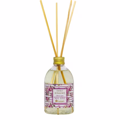 Difusor de ambiente Kailash Sweet Romance, com frasco de vidro transparente, rótulo com flores e texto em inglês, contendo líquido e varetas de madeira para perfumar o ambiente.